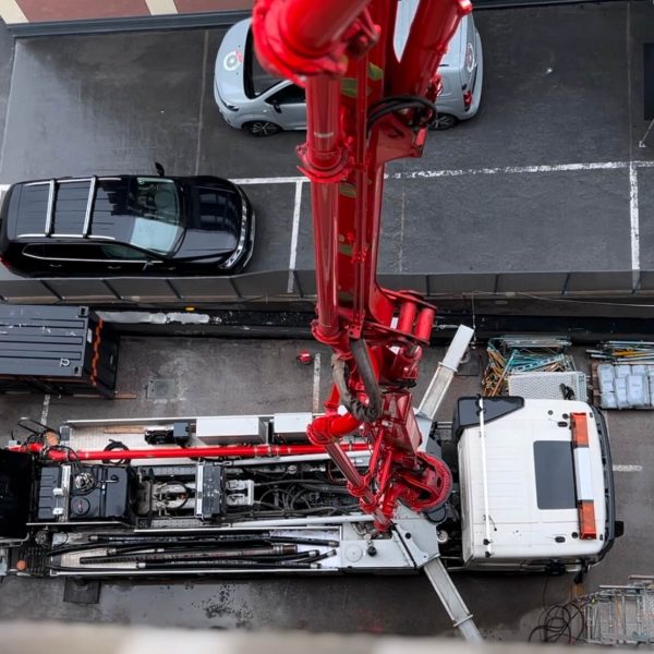 Betongpumpbil sedd uppifrån med bommen riktad upp mot byggnaden