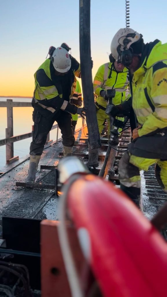 Betongarbetare styr pumpslangen under gjutning i soluppgången