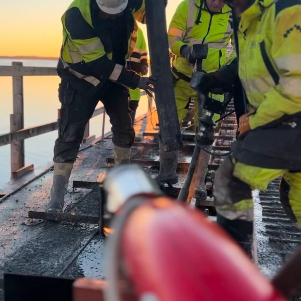 Betongarbetare styr pumpslangen under gjutning i soluppgången