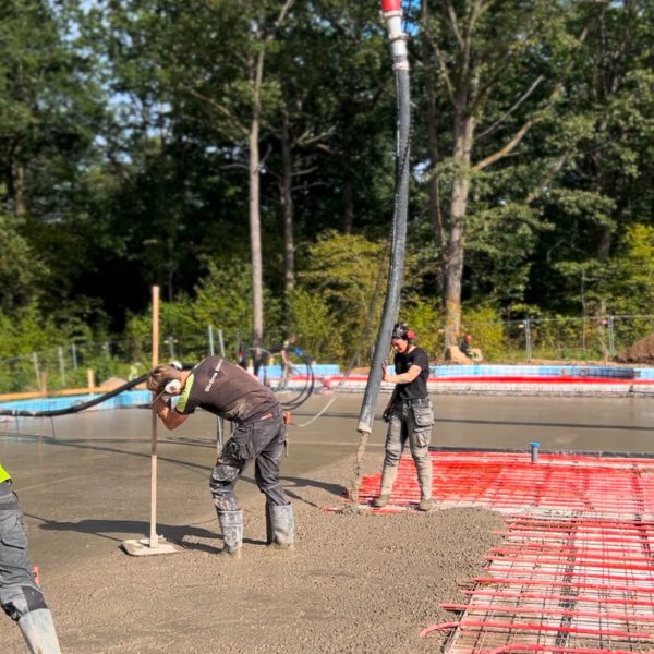 Betongpumpens bom når in över en platta medan betongen dras av
