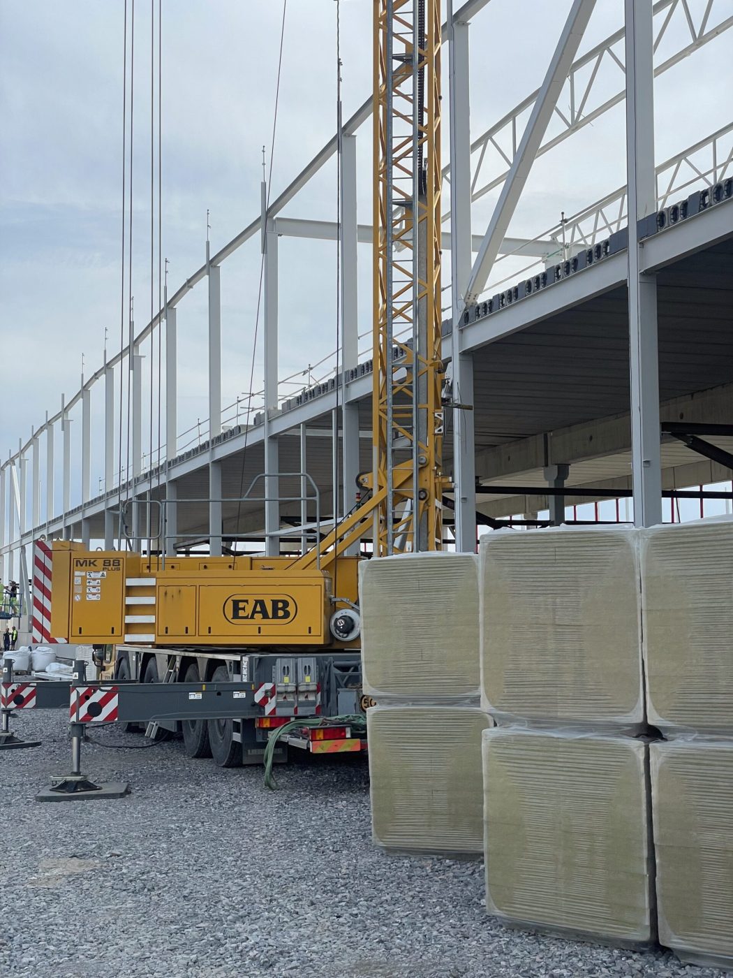 Stålstomme för en logistikhall under uppförande, med mobilkran i förgrunden