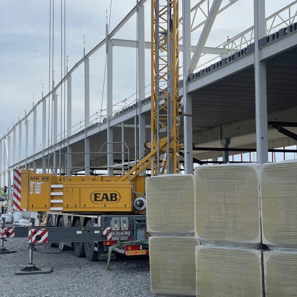Stålstomme för en logistikhall under uppförande, med mobilkran i förgrunden