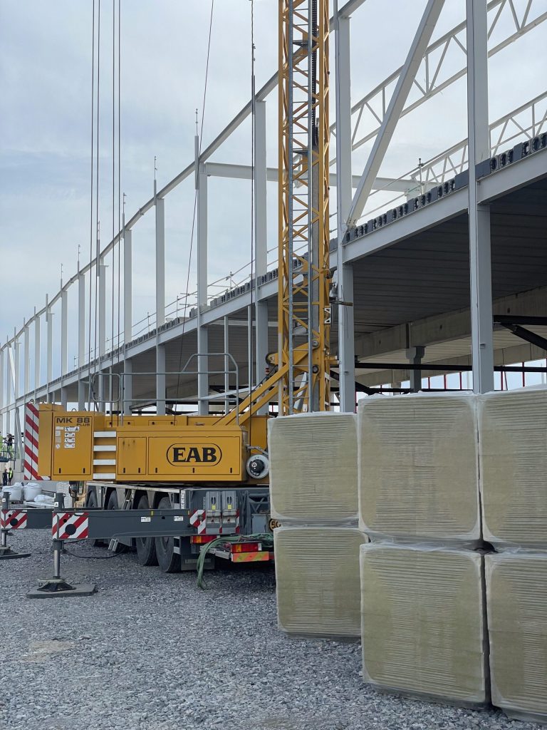 Stålstomme för en logistikhall under uppförande, med mobilkran i förgrunden