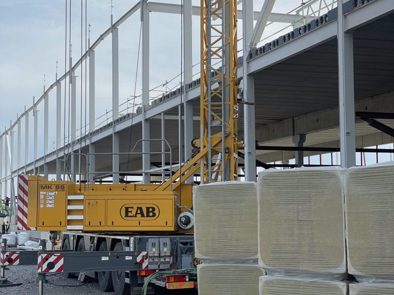 Stålstomme för en logistikhall under uppförande, med mobilkran i förgrunden
