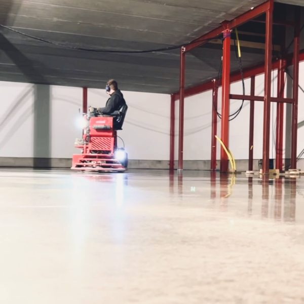 Glättning av ett nygjutet betonggolv med maskin i en industrihall
