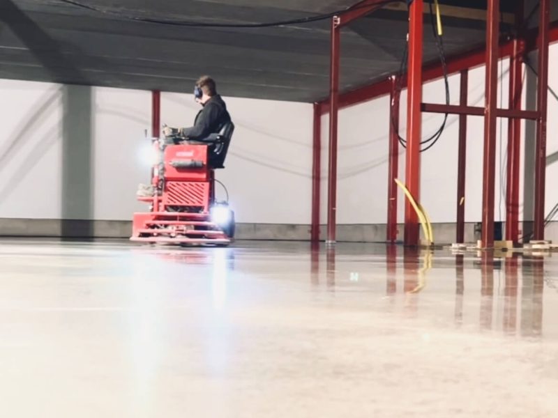 Glättning av ett nygjutet betonggolv med maskin i en industrihall