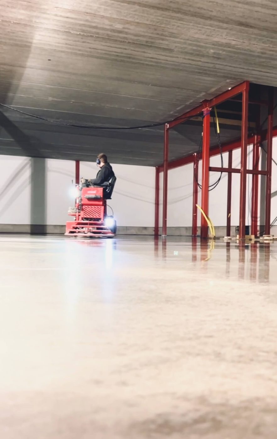 Glättning av ett nygjutet betonggolv med maskin i en industrihall