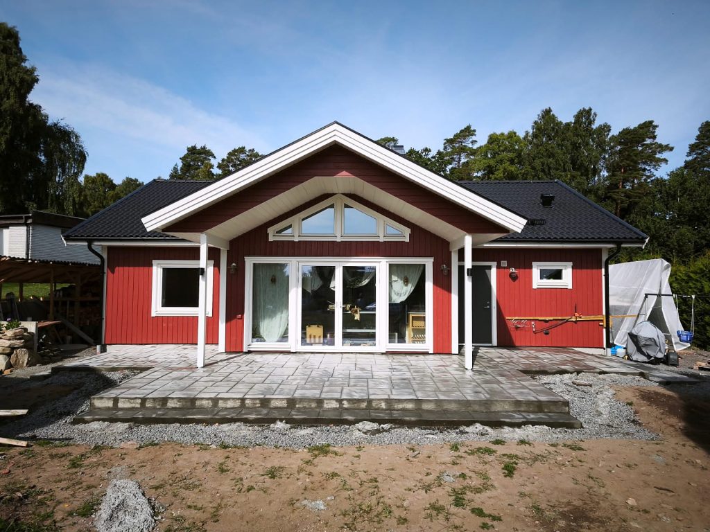 Uteplats i mönsterbetong med ashlarmönster framför ett rött hus