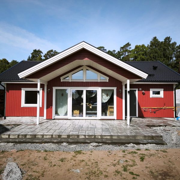 Uteplats i mönsterbetong med ashlarmönster framför ett rött hus