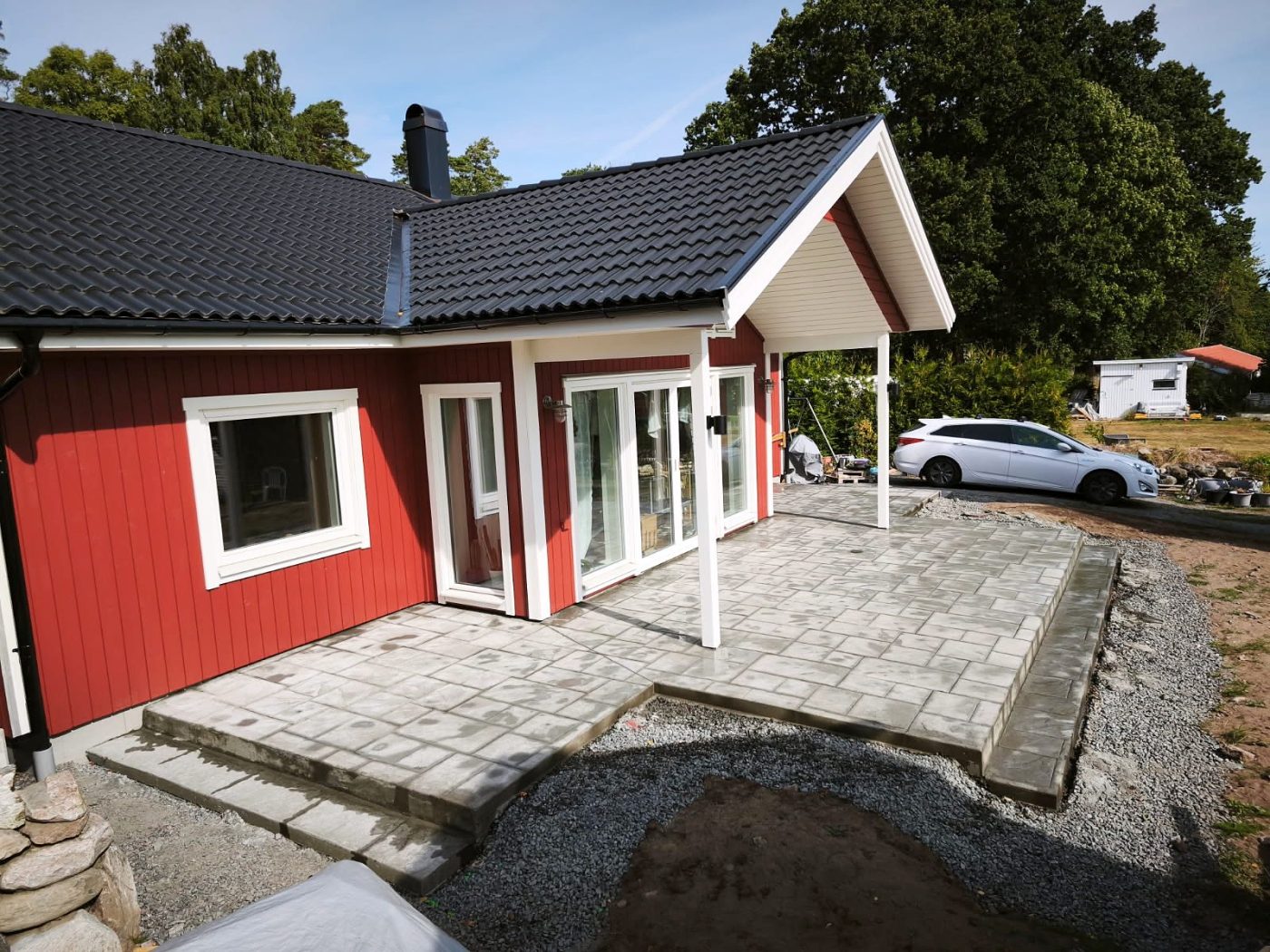 Uteplats i mönsterbetong med ashlarmönster vid ett rött hus