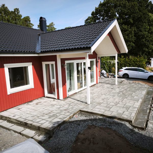 Uteplats i mönsterbetong med ashlarmönster vid ett rött hus