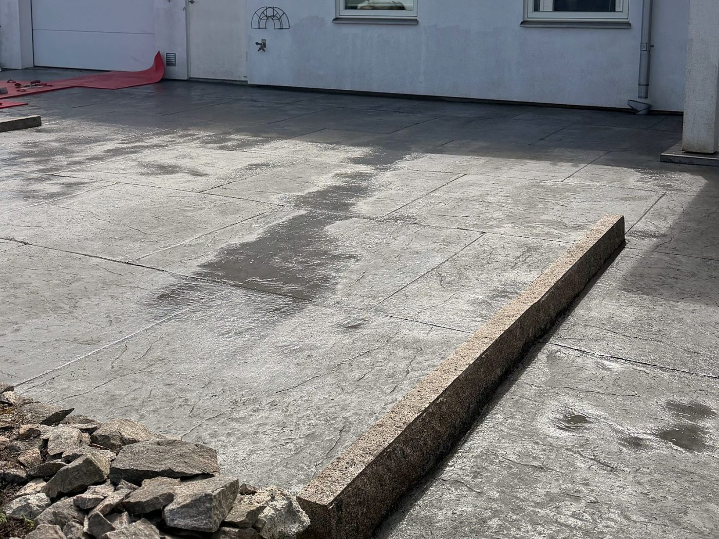 Uppfart i mönsterbetong med stora plattor framför garageporten på en vit villa