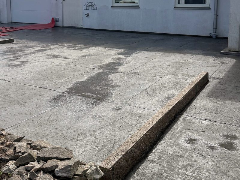 Uppfart i mönsterbetong med stora plattor framför garageporten på en vit villa