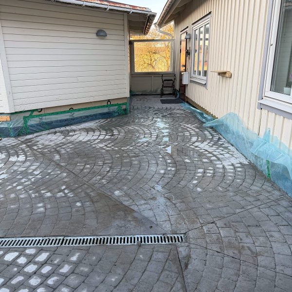 Gårdsplan i mönsterbetong med smågatsten i solfjädersmönster